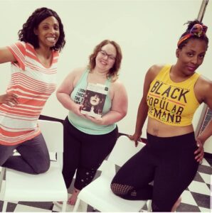 3 women in chair dance class, holding book.